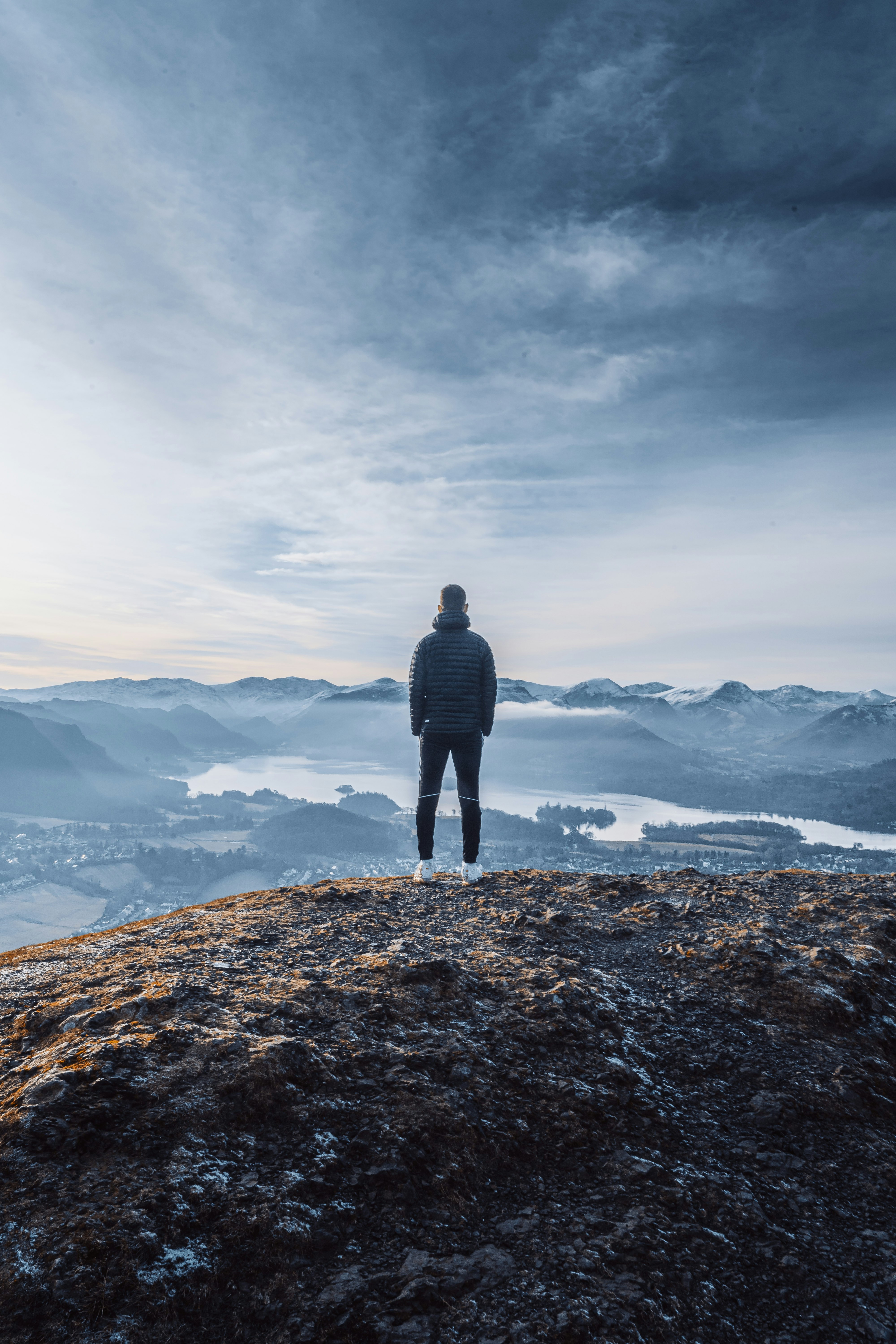 man in black jacket standing on brown rock formation during daytime